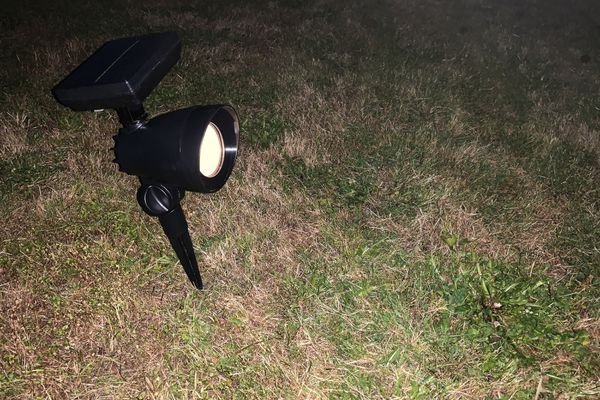 The Hampton Bay LED Outdoor Solar Spotlight powered on in grass