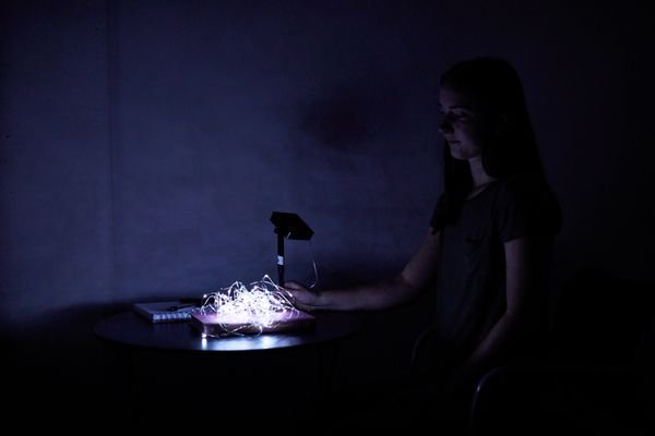 Person sitting down looking at the Brightown LED Solar Powered Fairy Lights on the table in the dark