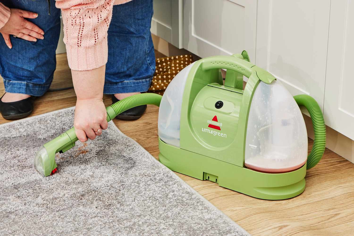 A person using the Bissell 1400B Little Green Multi-Purpose Portable Carpet and Upholstery Cleaner on carpet