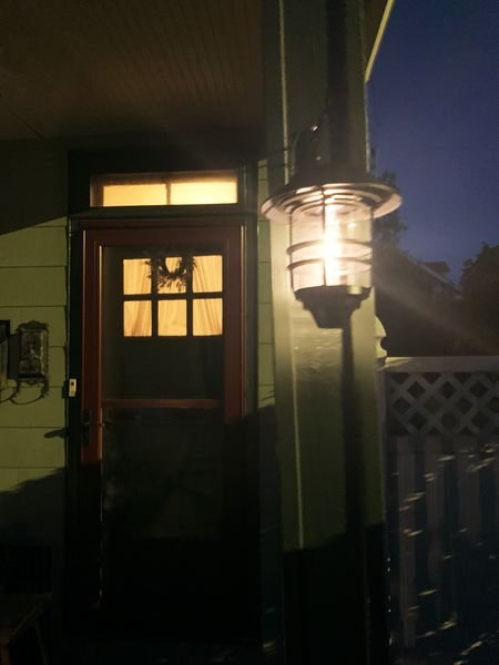 Derynome Solar Lantern Outdoor Lights with Wall Mount Kit on in the dark in front of a house 