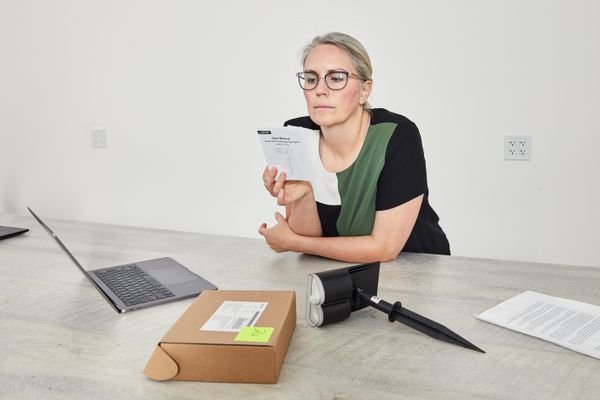 A person reading Linkind StarRay Solar Spotlights instructions next a spotlight and its packaging