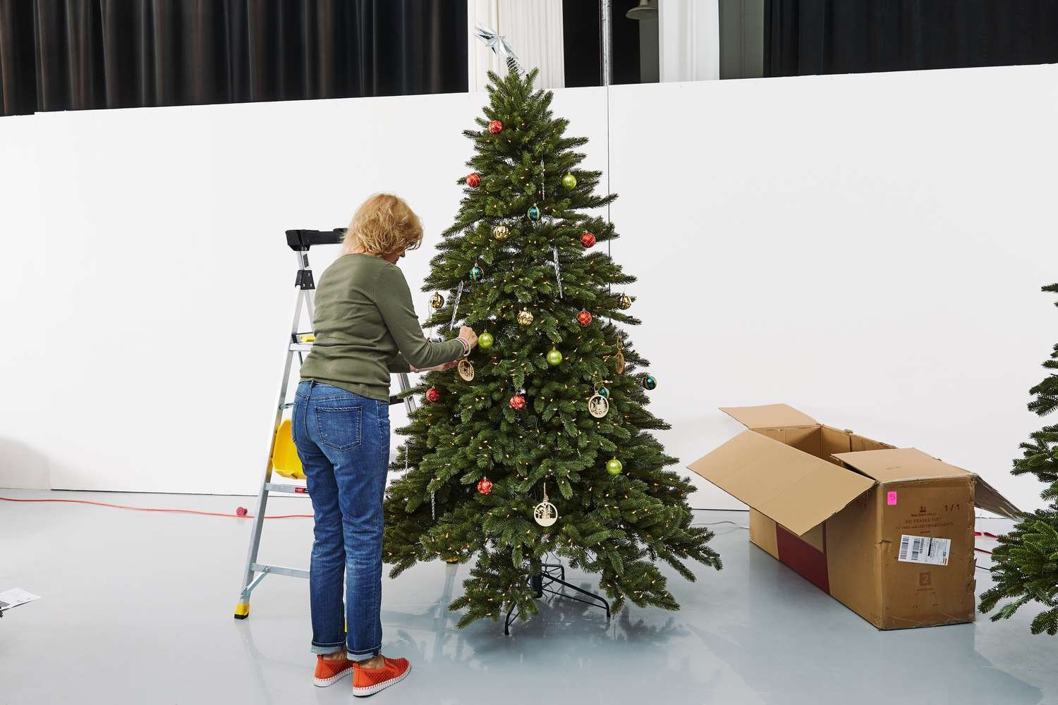 A person adding ornaments to the Balsam Hill Vermont White Spruce