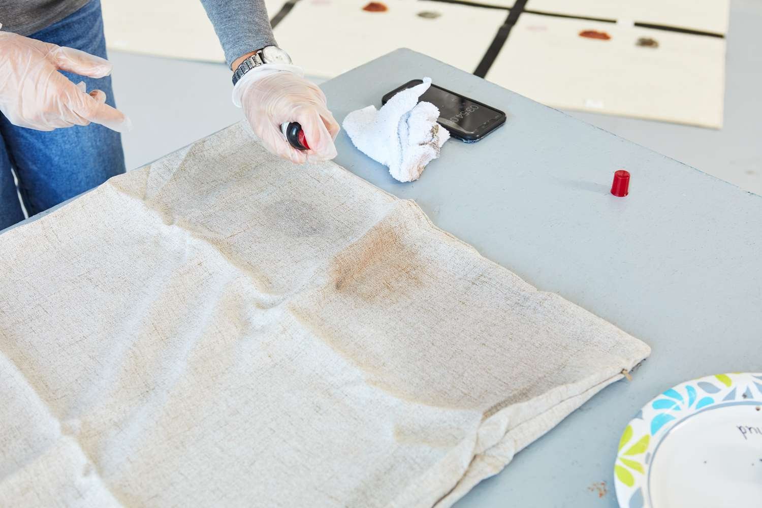 Person spraying stain on pillowcase with Emergency Stain Rescue Chateau Spill Red Wine Stain Remover