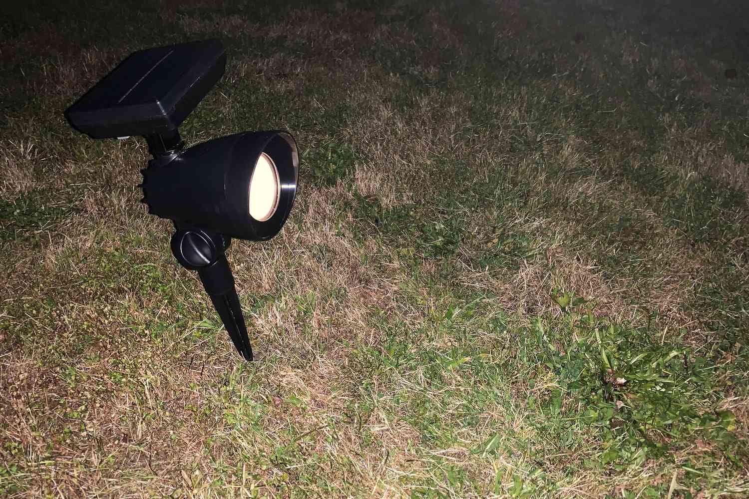 The Hampton Bay LED Outdoor Solar Spotlight powered on in grass