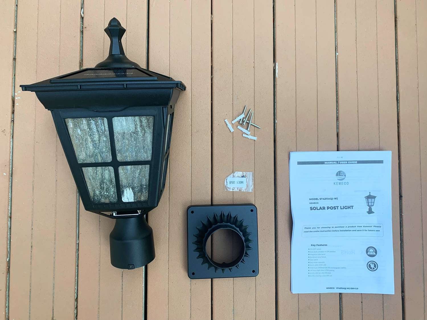 Instruction manual and screws next to the Kemeco Solar Post Light laid on a wooden floor