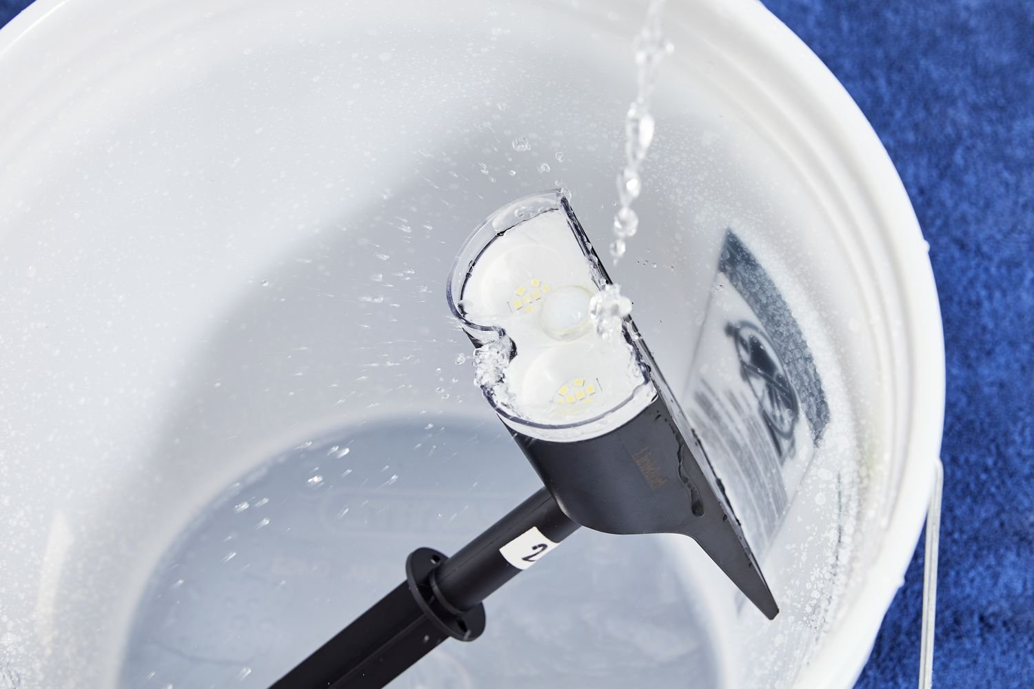 Water being poured over a Linkind StarRay Solar Spotlight into a bucket