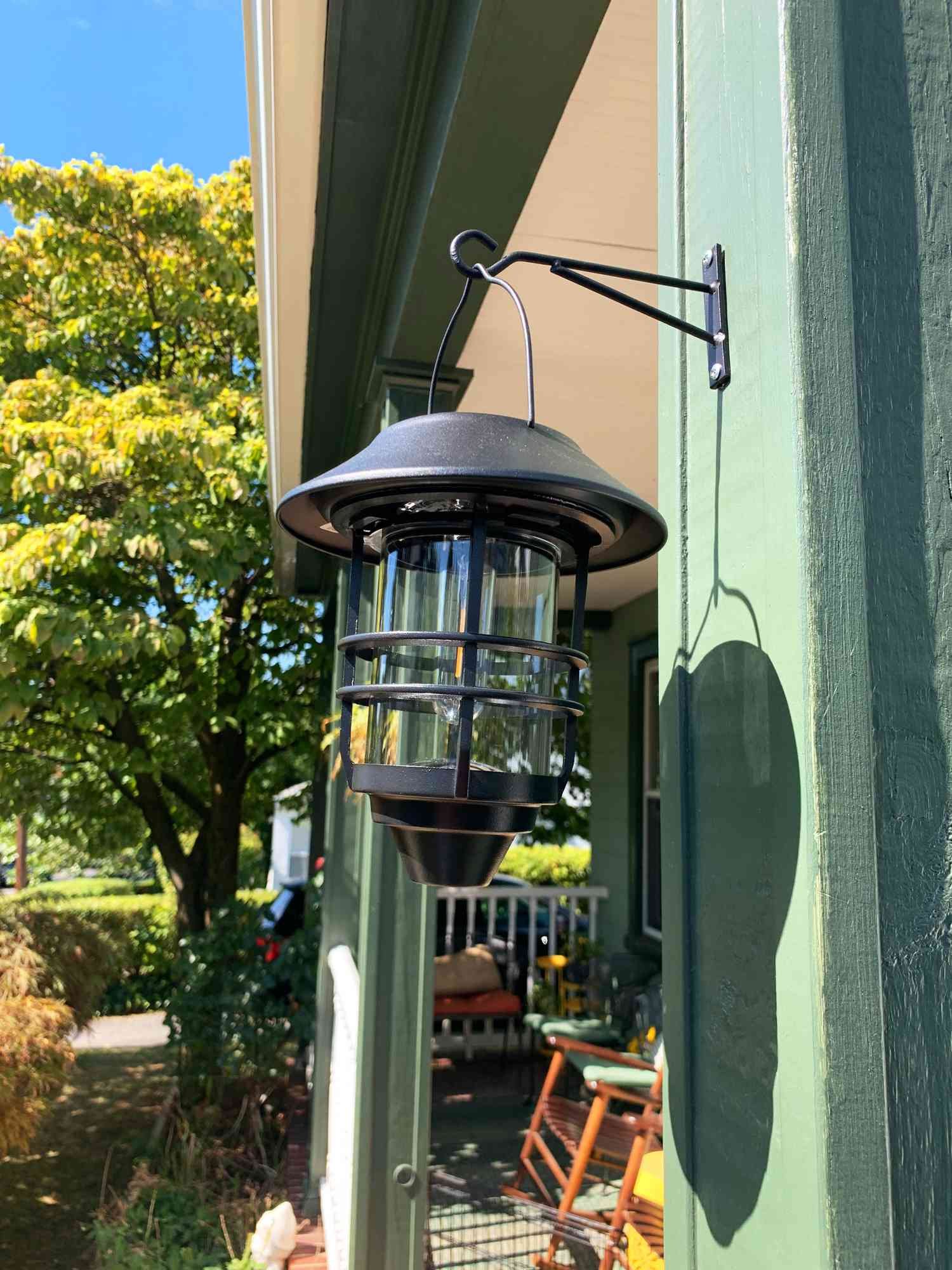 Derynome Solar Lantern Outdoor Lights with Wall Mount Kit hanging on a hook outside