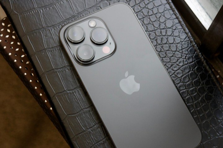 A black iPhone 14 Pro laying face-down on a black journal.