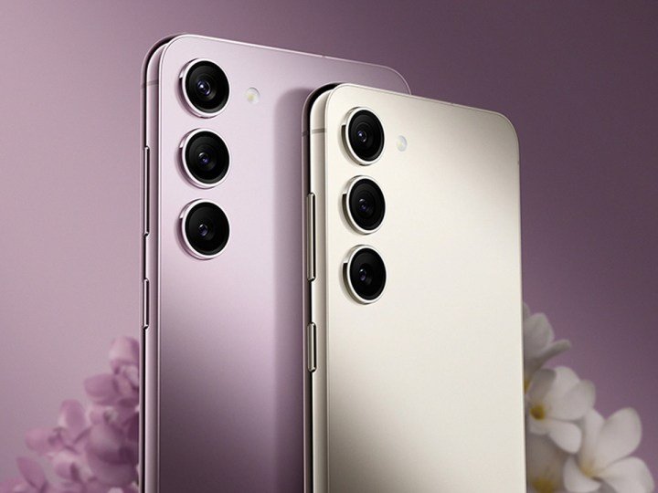 A couple different colors of the Samsung Galaxy S23 smartphone against a purple background.