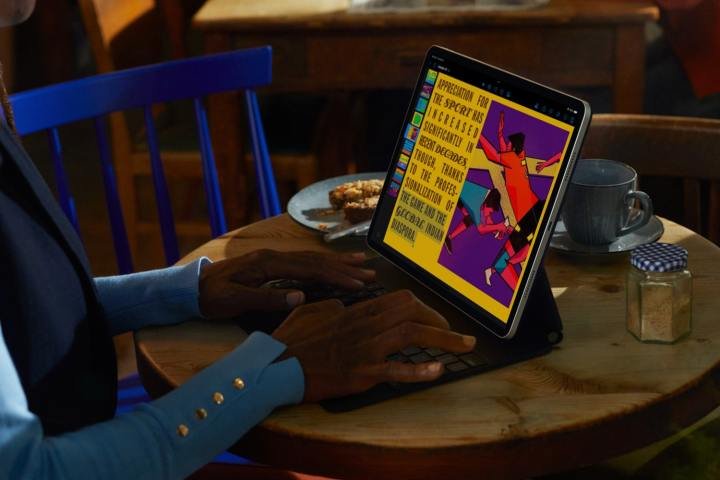 A person using Apple's iPad Pro with Magic Keyboard case on a desk.
