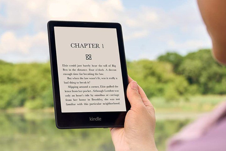 A person reads on an Amazon Kindle Paperwhite outdoors.