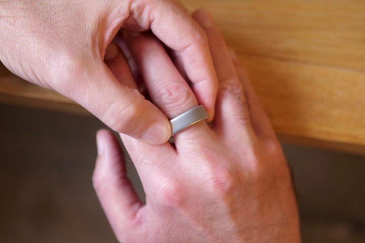 A person putting on the Oura Ring 4.