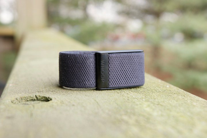The Whoop 4.0 lying on a wood railing.