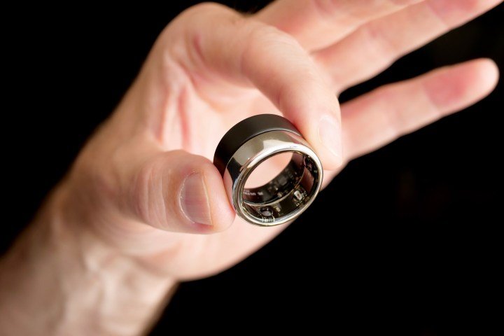 A person holding the Ultrahuman Ring Air and the Oura Ring.