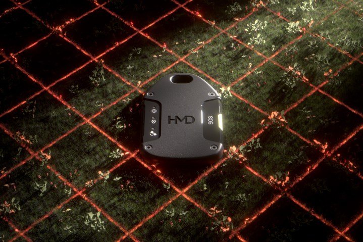 The HMD OffGrid laying on the grass surrounded by red lasers.