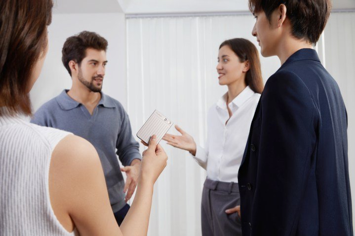 Four colleagues have a conversation around a Plaud Note AI notetaker.