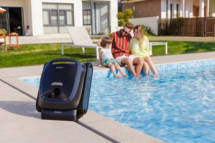 Beatbot c1000 pool cleaner on edge of pool with family of 3 in the background