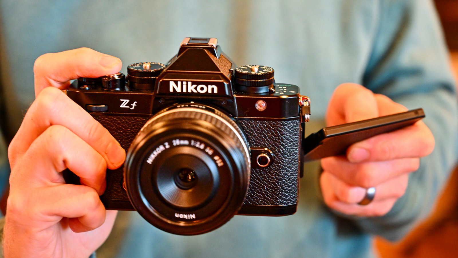 Nikon Zf camera in the hand with vari-angle screen out to the side and with Z 28mm F2.8 SE lens attached