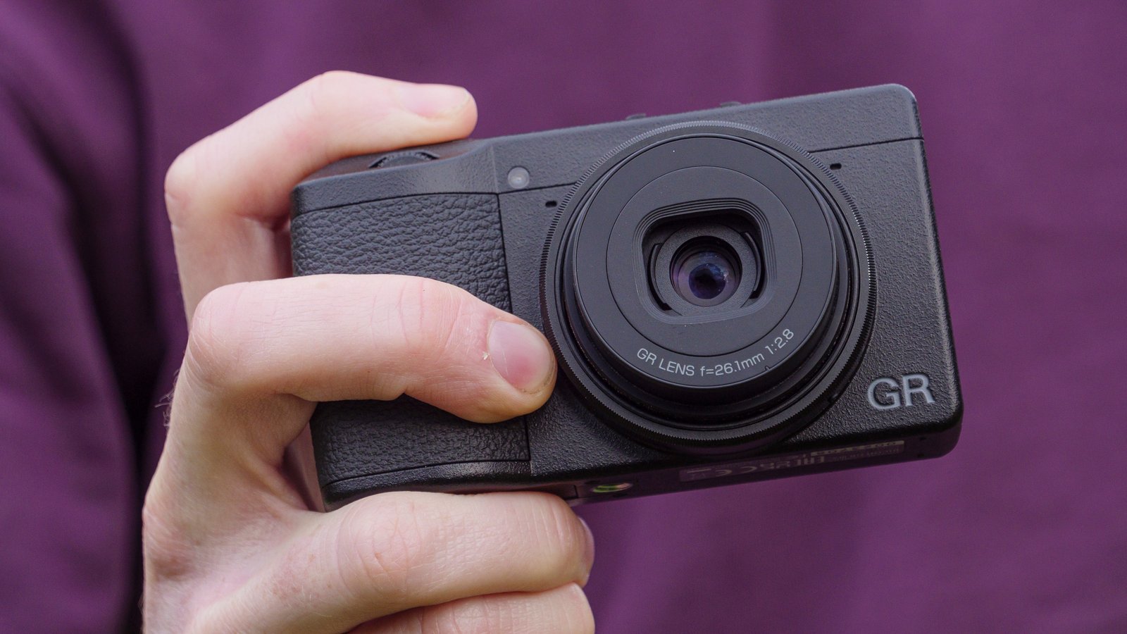 A hand holding the Ricoh GR IIIx camera